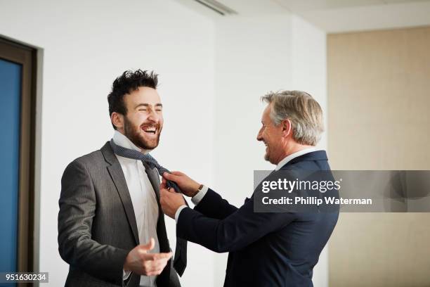 Senior businessman fastening colleagues tie in office
