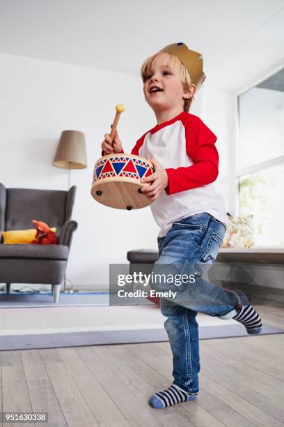 young boy wearing cardboard crown, beating toy drum, low angle view - trommel stock-fotos und bilder