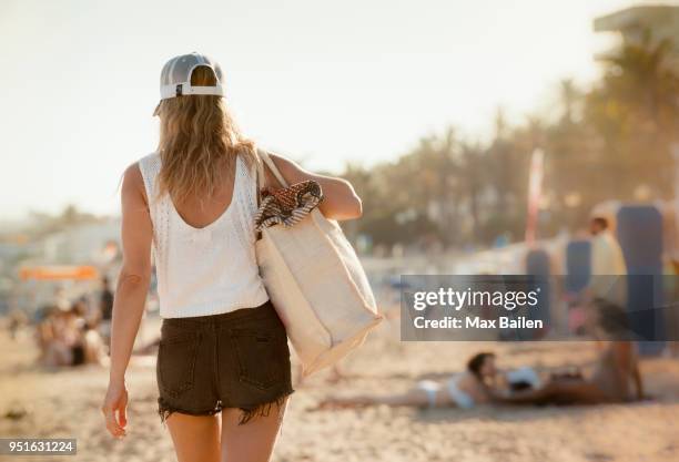 woman walking along beach, rear view, sitges, catalonia, spain - beach bag foto e immagini stock