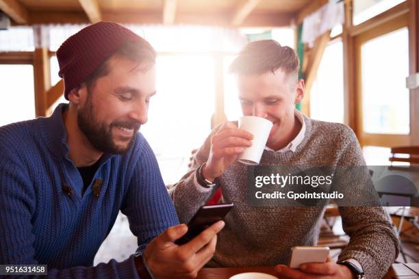 young men smiling over text message on mobile phones - gpointstudio imagens e fotografias de stock