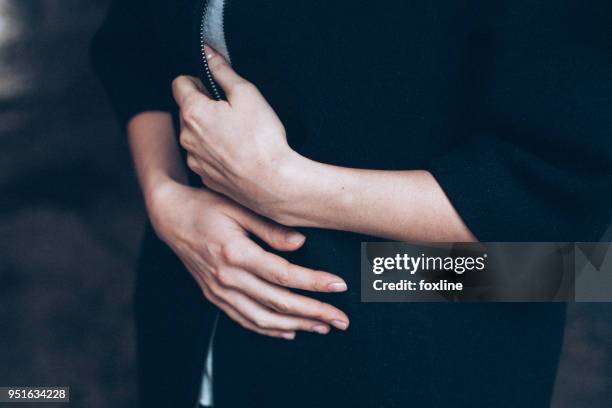 woman holding her coat with her hands on stomach - hands on tummy stock pictures, royalty-free photos & images