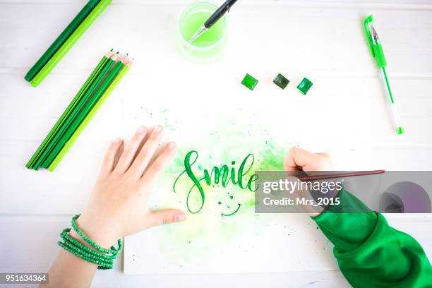 boy writing the word smile with watercolor paint - hand smile painted stock-fotos und bilder