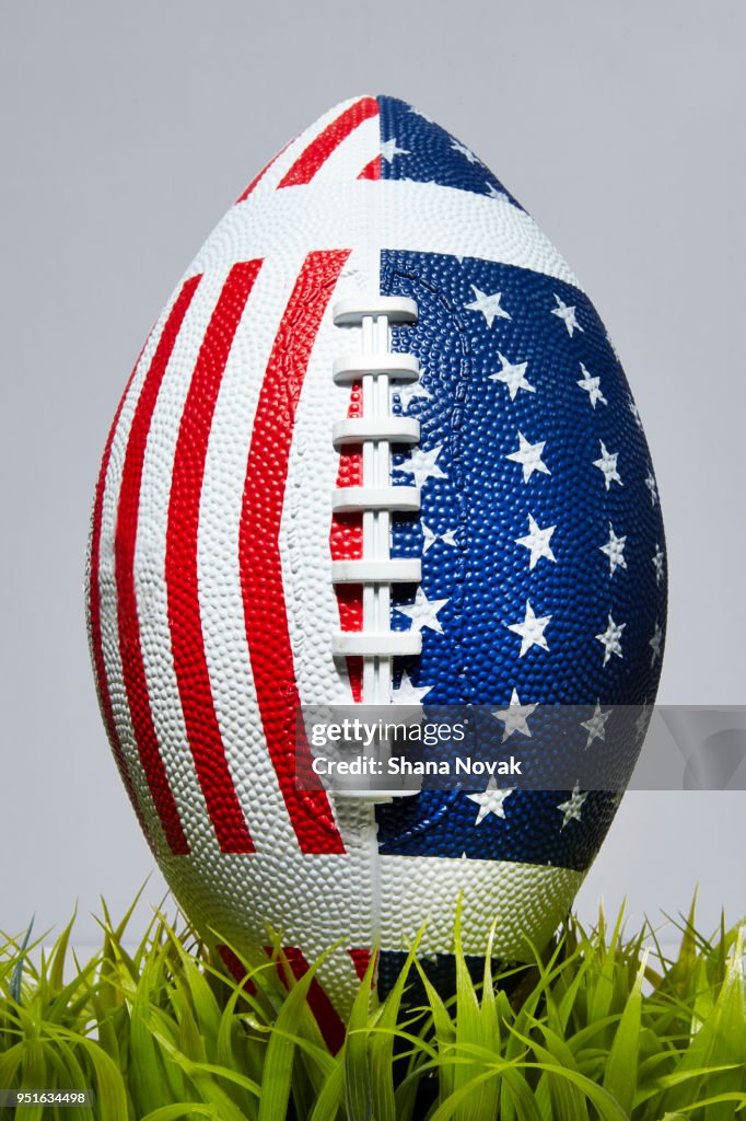 Football with American Stars and Stripes in Grass