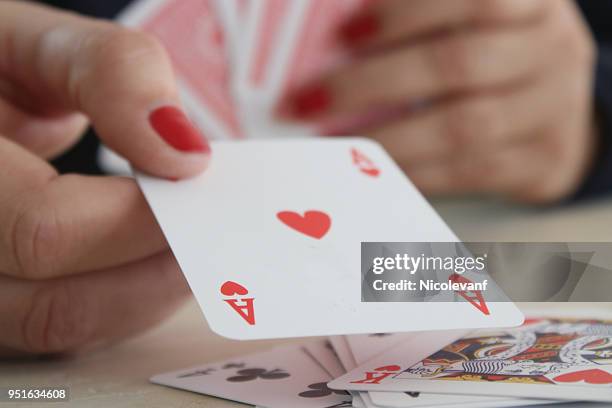 womans hand holding an ace of hearts playing card - aas kaarten stockfoto's en -beelden