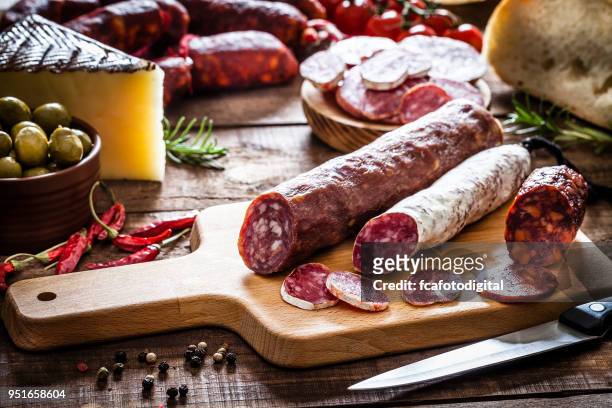 mixed spanish chorizo pieces on rustic wooden table - salami stock pictures, royalty-free photos & images
