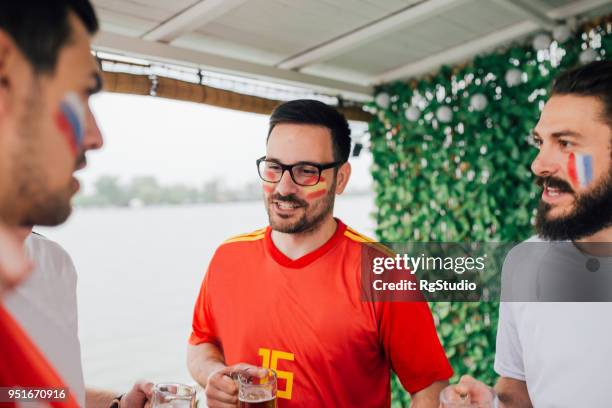 man supporting spanish national soccer team having conversation with friends - france national soccer team stock pictures, royalty-free photos & images