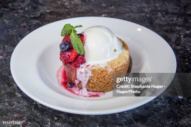 warm butter cake our signature warm butter cake, crystallized sugar crust,  häagen-dazs vanilla ice cream, garnished with berry compote - ice cream cake stock pictures, royalty-free photos & images