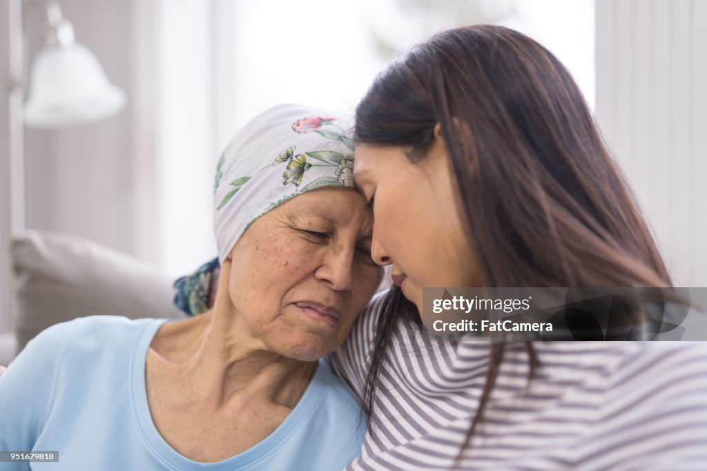 Ethnic elderly woman with cancer embracing her adult daughter