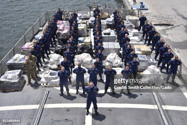 United States Coast Guard crew standing with $390 million in confiscated cocaine and marijuana from Mexican and Central American smugglers, at sea,...