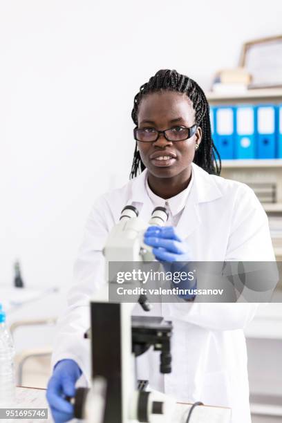 weibliche labor arbeiter mit mikroskop - adenovirus stock-fotos und bilder