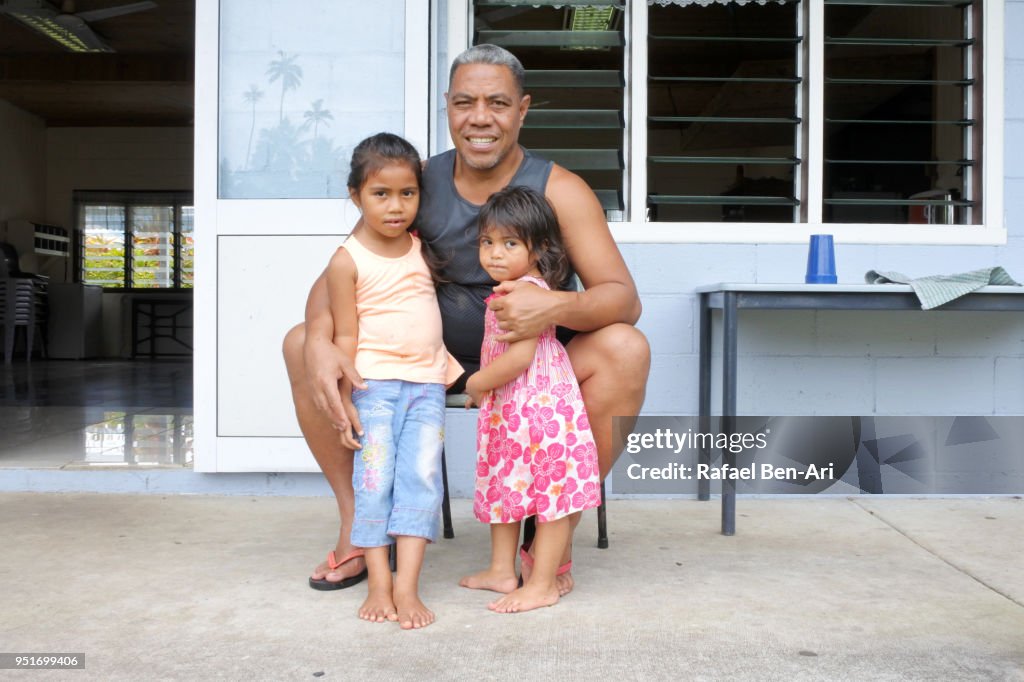 Pacific Islander father hugs his two little daughters