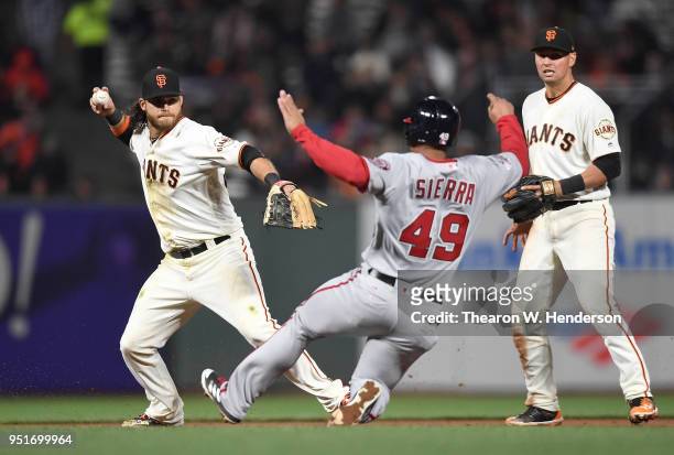 Brandon Crawford of the San Francisco Giants looks to throw over the top of Moises Sierra of the Washington Nationals to complete the double-play in...