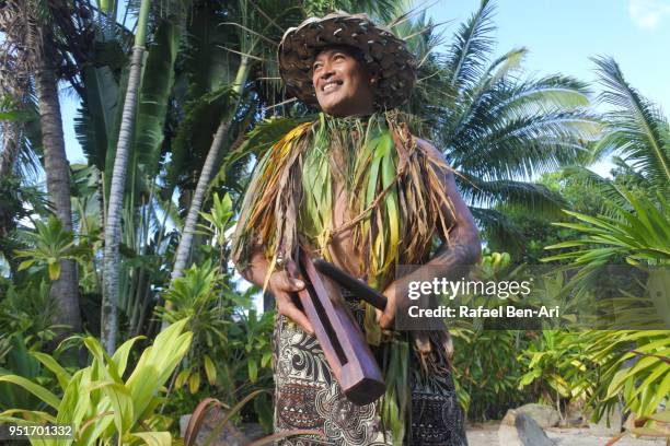 pacific islander man plays music on a small pate wooden stick drum instrument in rarotonga cook islands - oceania foto e immagini stock