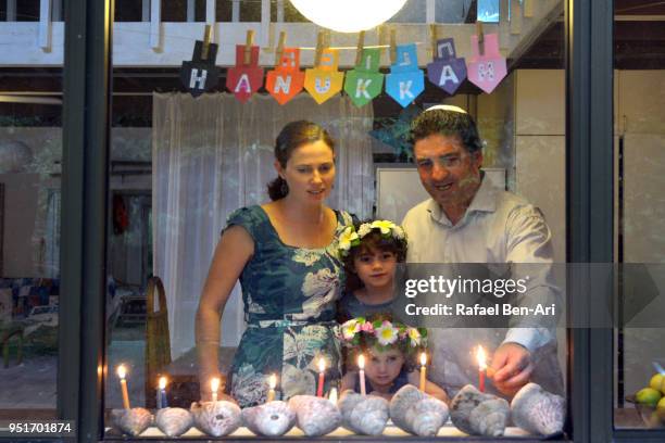 Jewish family lights the final candle on the menorah on the last day of Hanukkah Jewish holiday