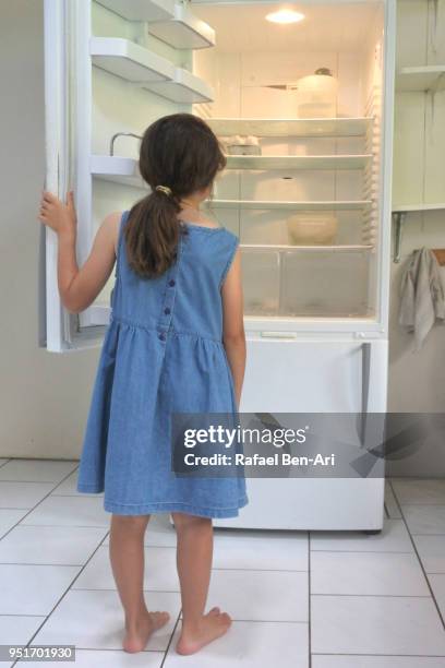 hungry poor sister girl looks for food in empty fridge at home - kühlschrank leer stock-fotos und bilder