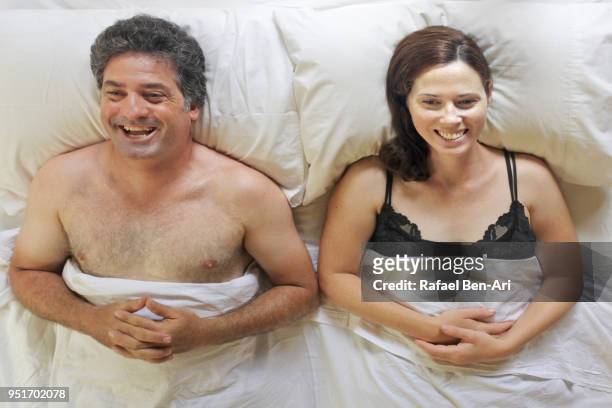 above view of happy man and woman lying in bed - rafael ben ari fotografías e imágenes de stock