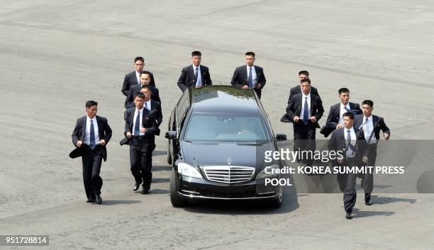North Korean bodyguards jog next to a car carrying North Korea's leader Kim Jong Un returning to the North for a lunch break after a morning session...