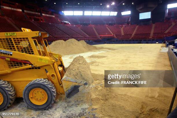 Une pelleteuse décharge, le 20 novembre 2002, du sable dans la fosse du Palais Omnisports de Paris-Bercy pour préparer le terrain de tennis sur...