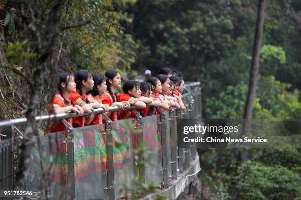 Girls of Yao ethnic group pose for photos to welcome the opening of a glass walkway at Jiulong River National Forest Park of Rucheng County on April...