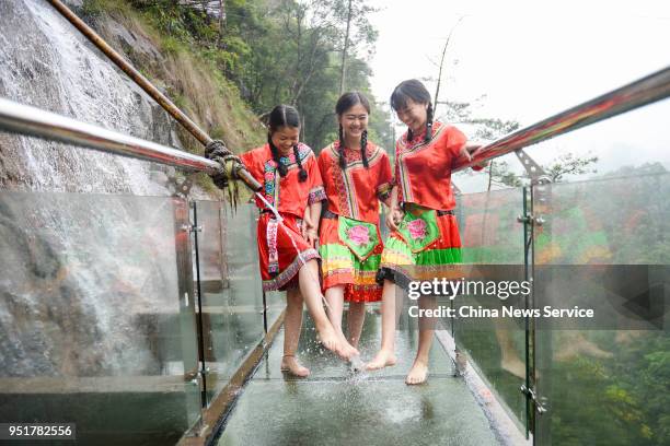 Girls of Yao ethnic group pose for photos to welcome the opening of a glass walkway at Jiulong River National Forest Park of Rucheng County on April...