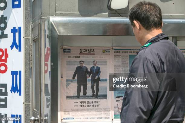 Man looks at a copy of Munhwa Ilbo newspaper, featuring photographs of Moon Jae-in, South Korea's President, right, and Kim Jong Un, North Korea's...