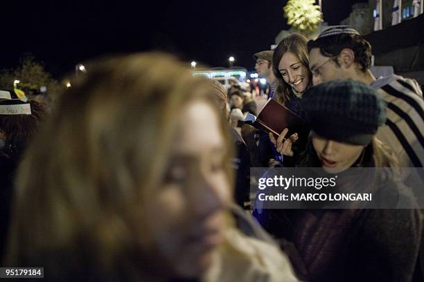 Jewish couple, covered with a prayer shawl worn customarily by men only, attend a prayer service at the Western Wall Plaza held by the "Women at the...