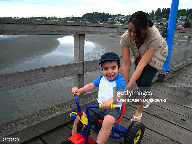 mom pushing son on bike - white rock bc stock pictures, royalty-free photos & images