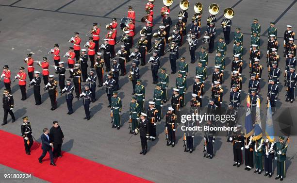 Moon Jae-in, South Korea's president, bottom, and Kim Jong Un, North Korea's leader, walk along a red carpet together during an honor guard ceremony...