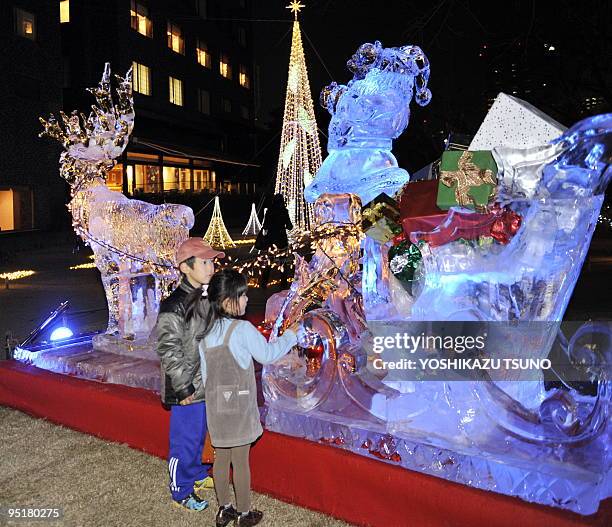 Children stand by illuminated ice sculptures shaped as reindeer in the garden of Tokyo's Takanawa Prince Hotel on December 24, 2009. AFP PHOTO /...