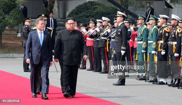 Moon Jae-in, South Korea's president, left, and Kim Jong Un, North Korea's leader, walk along a red carpet together during an honor guard ceremony in...
