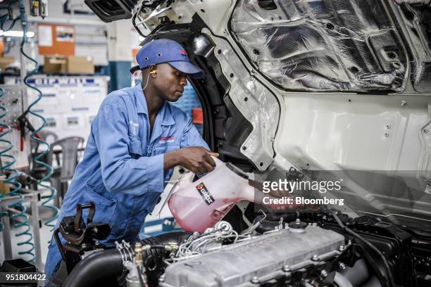 An employee adds antifreeze and coolant solution to the OHC diesel engine of an Isuzu NPR N-Series truck on the assembly line inside the Isuzu East...