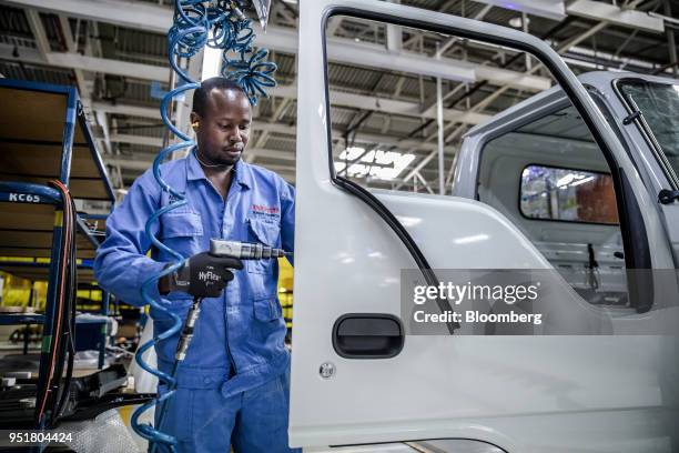 An employee installs parts to a door panel of an Isuzu FSR 33H F-Series truck on the assembly line inside the Isuzu East Africa Ltd. Plant in...