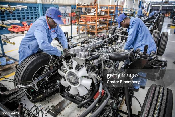 Employees install an Isuzu OHC diesel engine onto a chassis on the assembly line inside the Isuzu East Africa Ltd. Plant in Nairobi, Kenya, on...