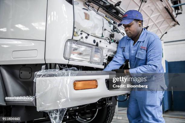 An employee affixes a bumper on an Isuzu FSR 33H F-Series truck cabin on the assembly line inside the Isuzu East Africa Ltd. Plant in Nairobi, Kenya,...