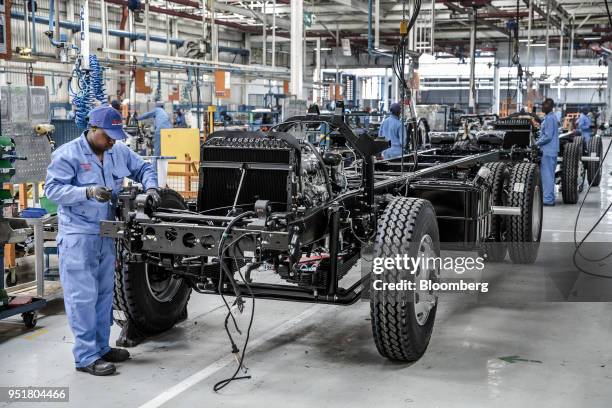 An employee affixes electronics to the chassis of an Isuzu truck on the assembly line inside the Isuzu East Africa Ltd. Plant in Nairobi, Kenya, on...