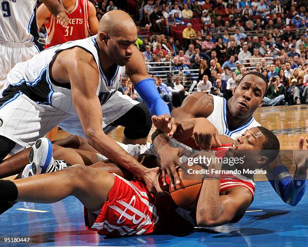 Kyle Lowry of the Houston Rockets gets tied up by Vince Carter and Dwight Howard of the Orlando Magic during the game on December 23, 2009 at Amway...