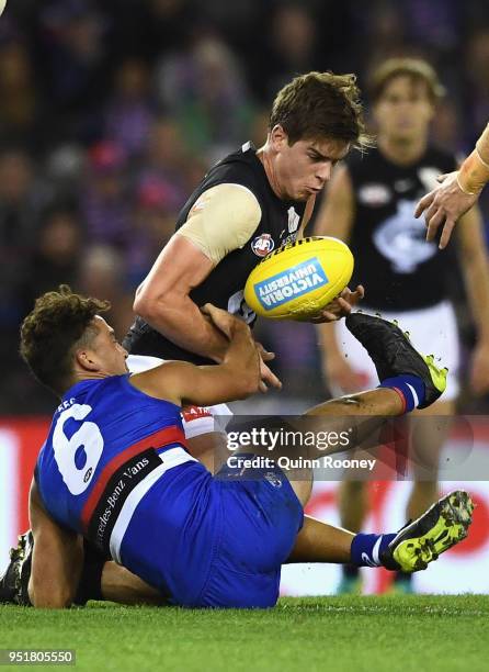 Paddy Dow of the Blues handballs whilst being tackled by Luke Dahlhaus of the Bulldogs during the AFL round six match between the Western Bulldogs...