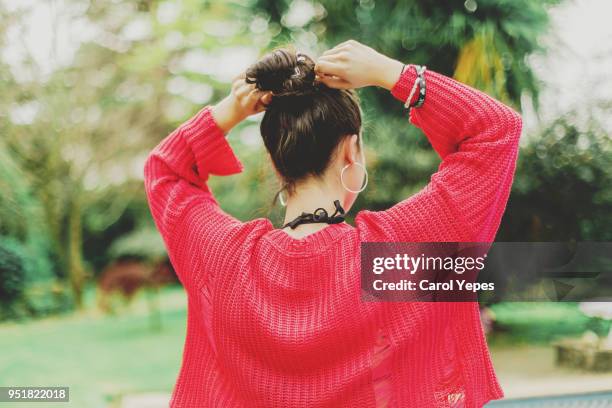 rear view young brunette outdoors making herself a bun - summer hair bun stock pictures, royalty-free photos & images