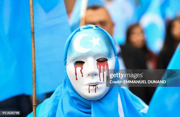 Person wearing a white mask with tears of blood takes part in a protest march of ethnic Uighurs asking for the European Union to call upon China to...