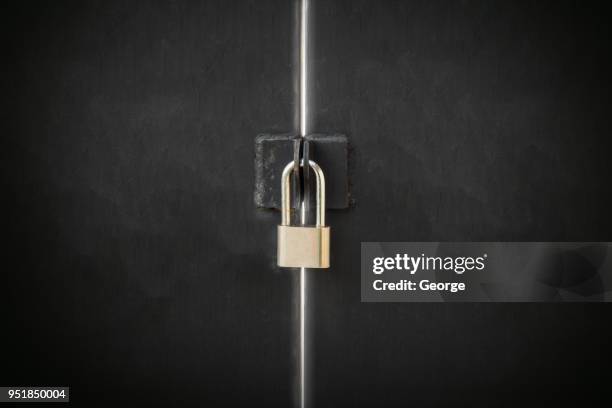 close-up of silver padlock and black steel door - serrure photos et images de collection