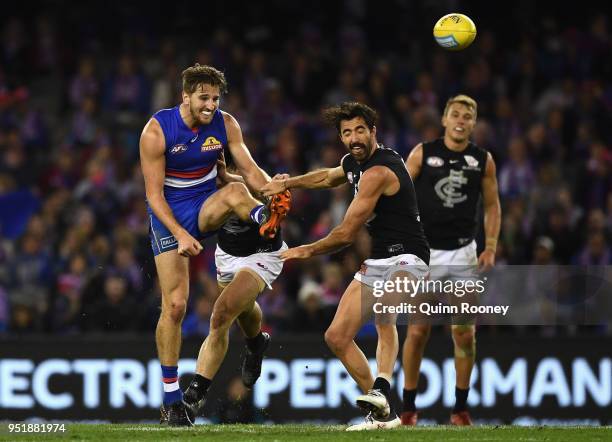 Marcus Bontempelli of the Bulldogs kicks whilst being tackled during the AFL round six match between the Western Bulldogs and Carlton Blues at Etihad...