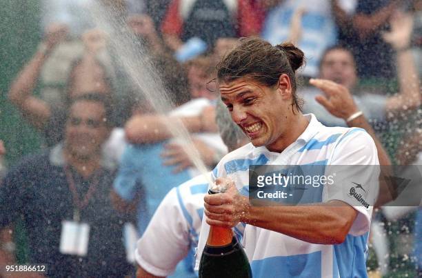Argentinian Gastón Gaudio celebrates his victory against Ivo Karlovic of Croatia with champagne 07 April 2002 at the Lawn Tennis Club of Buenos...