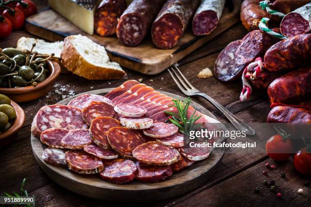 mixed spanish chorizo slices plate on rustic wooden table - sausage stock pictures, royalty-free photos & images