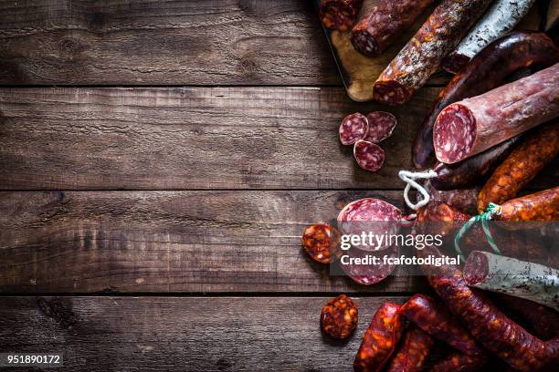 mixed spanish chorizo pieces border on rustic wooden table - raw sausages stock pictures, royalty-free photos & images