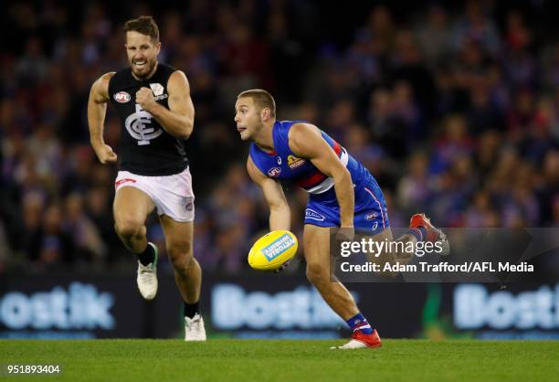 Caleb Daniel of the Bulldogs handpasses the ball ahead of Matthew Wright of the Blues during the 2018 AFL round six match between the Western...