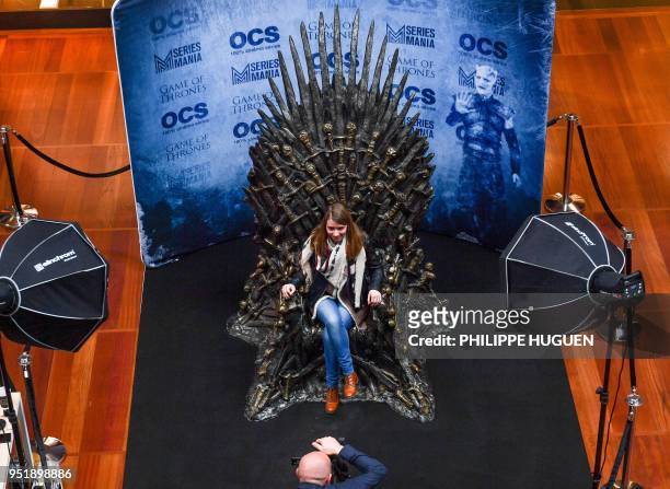 Woman sits on the throne of the US television serie Game of Thrones as she poses for a photography, at the Series Mania festival dedicated to TV...