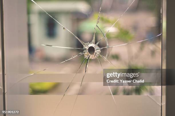 bullet hole on glass window - bullet holes stock-fotos und bilder