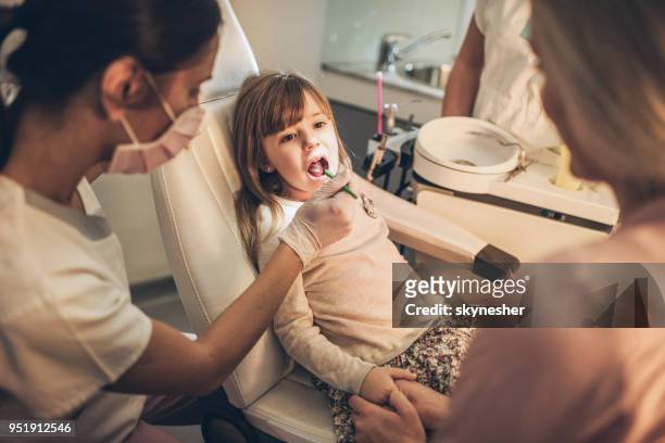 little girl having dental appointment with a support of her mother. - plaque remover stock pictures, royalty-free photos & images