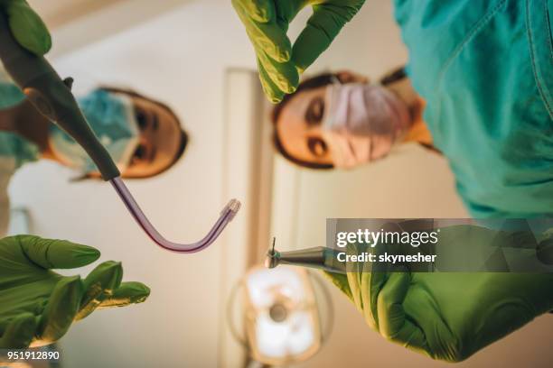 close up of female dentist and her assistant during dental procedure. - plaque remover stock pictures, royalty-free photos & images