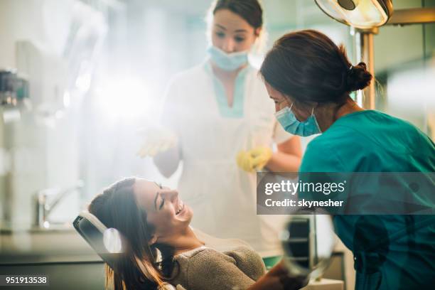 junge glückliche frau zum zahnarzt vor der zahnärztlichen behandlung sprechen. - dental hygienist stock-fotos und bilder